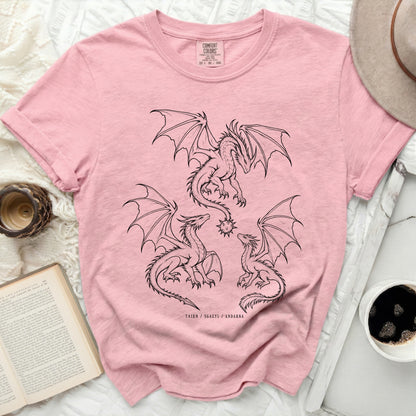 Pink t-shirt with three black line drawing dragons, one large and two smaller, and text.