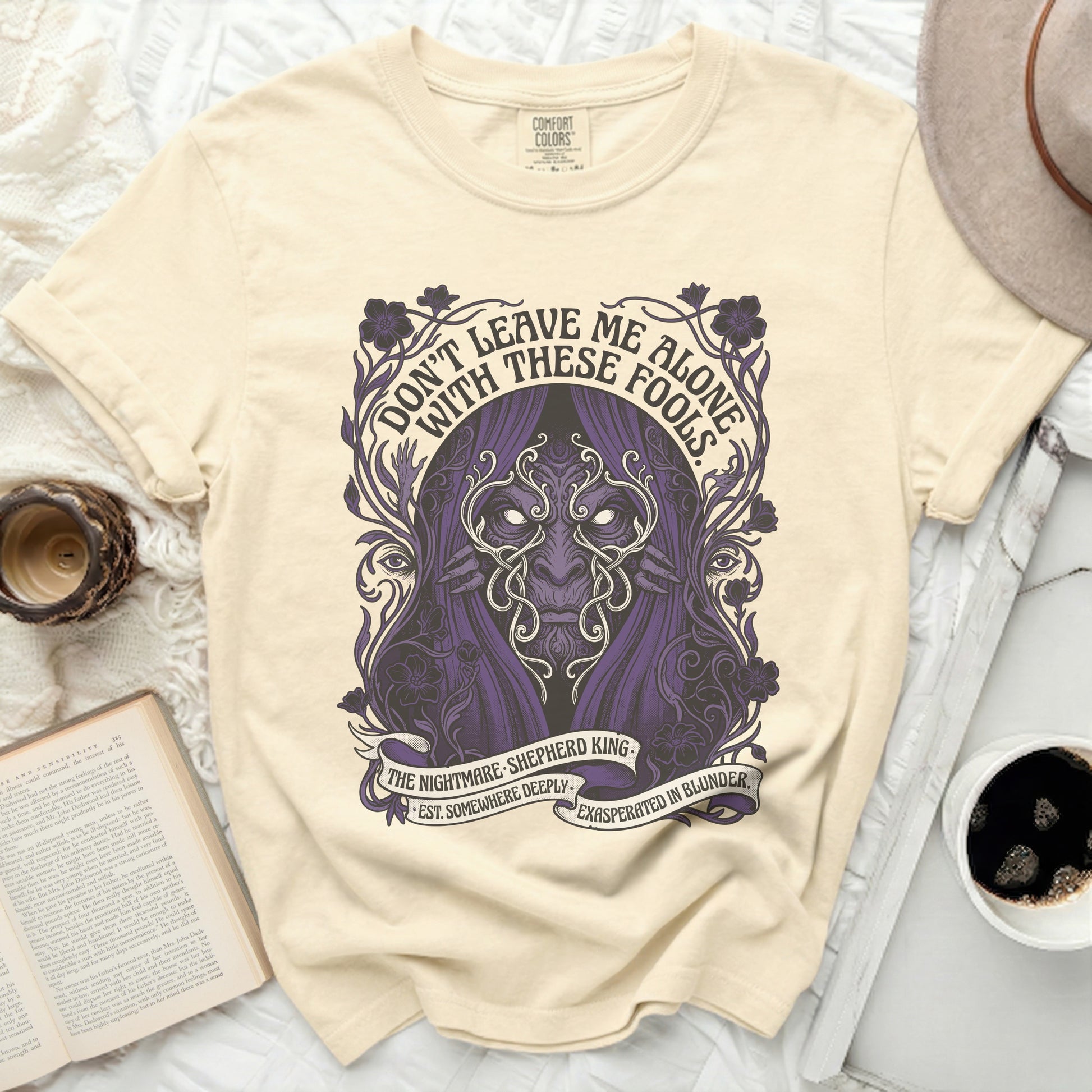 Cream t-shirt with purple gothic design and text.