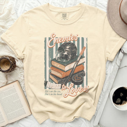 T-shirt with "Enemies to Lovers" text, hockey helmet, and books.