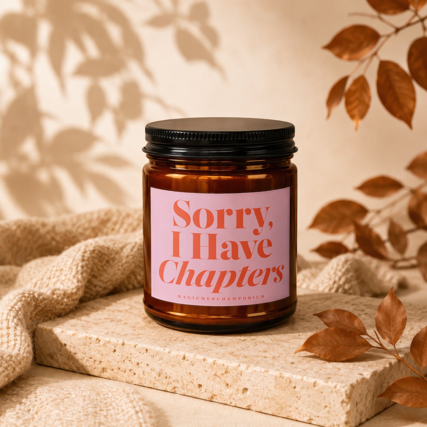 Amber jar candle with pink label reading "Sorry, I Have Chapters".