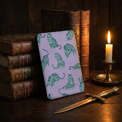 Purple case with a pattern of teal tigers, stacked antique books, and a lit candle.