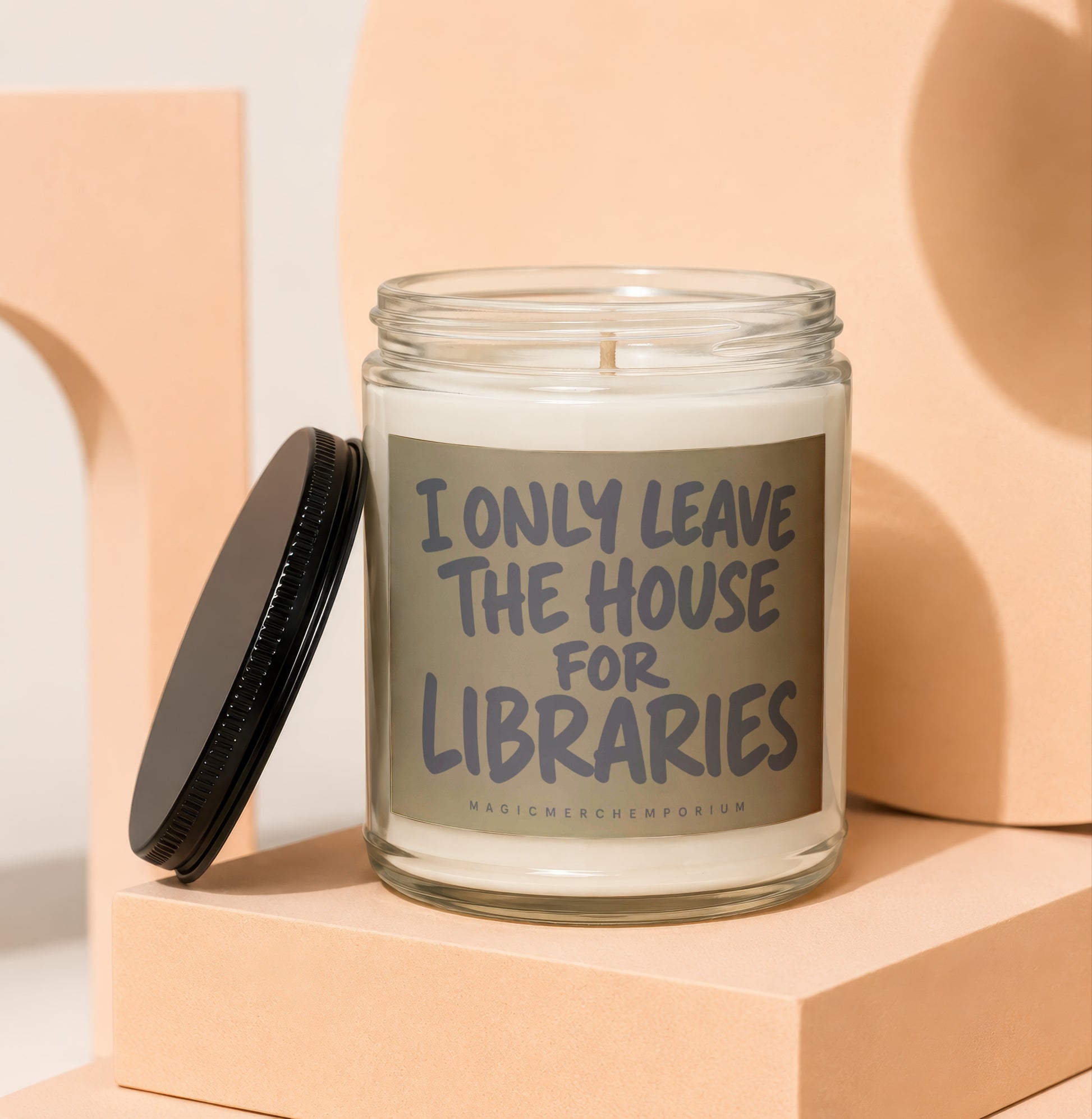 Glass jar candle with "I only leave the house for libraries" text and black lid.