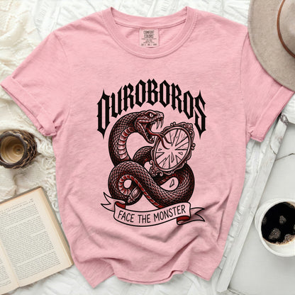 Pink t-shirt with a snake and mirror graphic that says "OUROBOROS FACE THE MONSTER".
