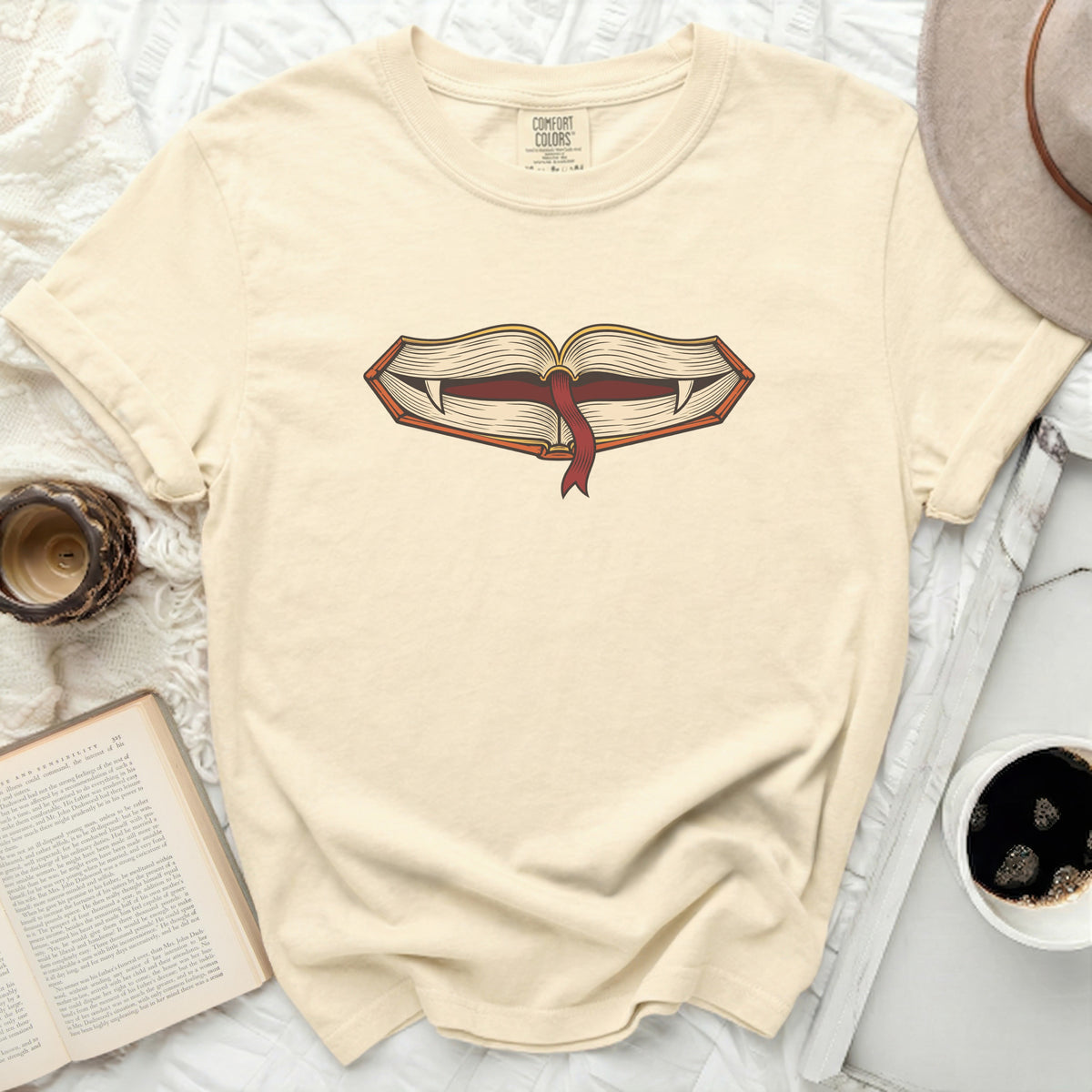 Cream t-shirt with open book graphic featuring vampire fangs.