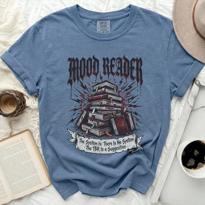 Blue t-shirt with "Mood Reader" and books, "The System Is: There Is No System" on a banner.
