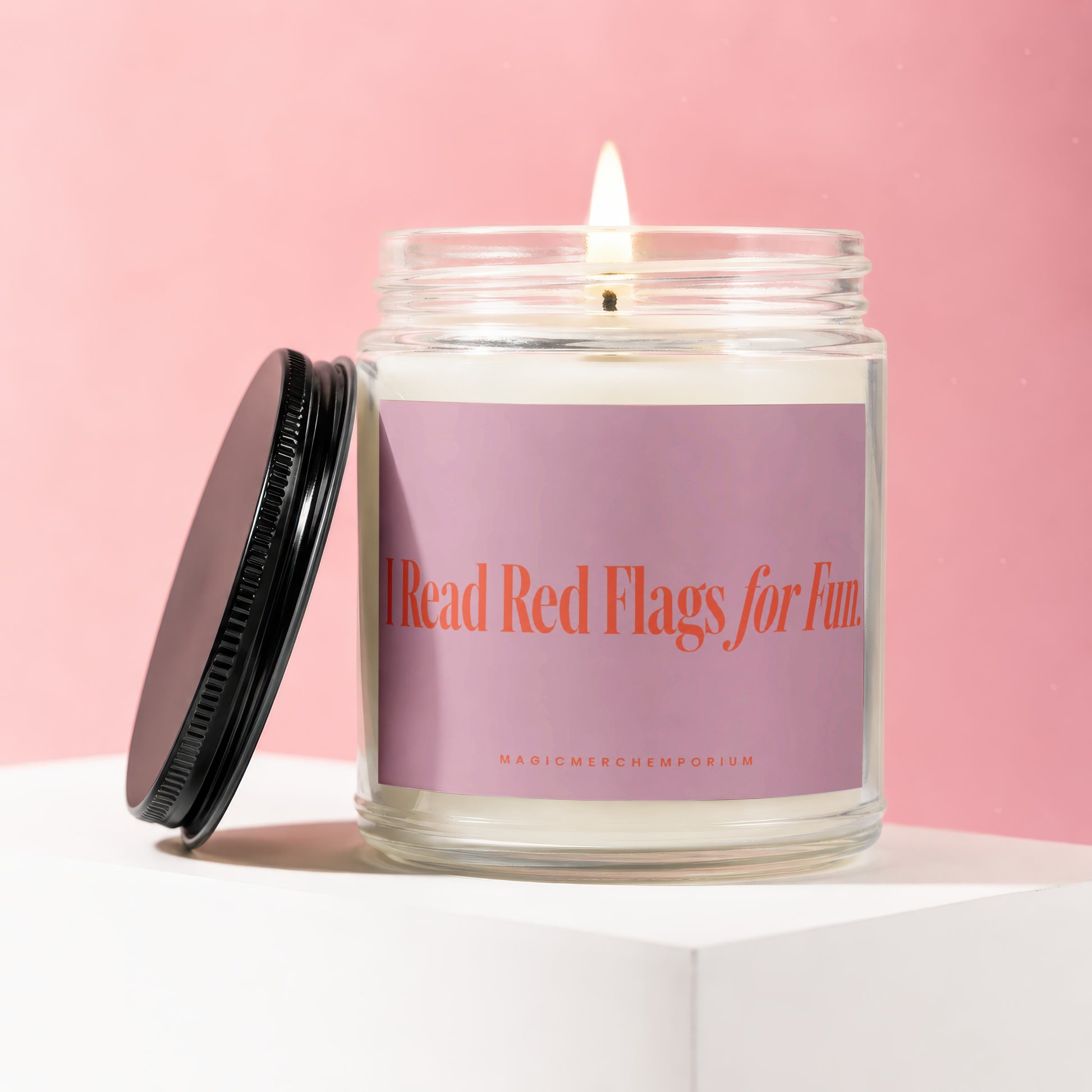 Glass jar candle with lit wick and black lid, reading "I Read Red Flags for Fun."