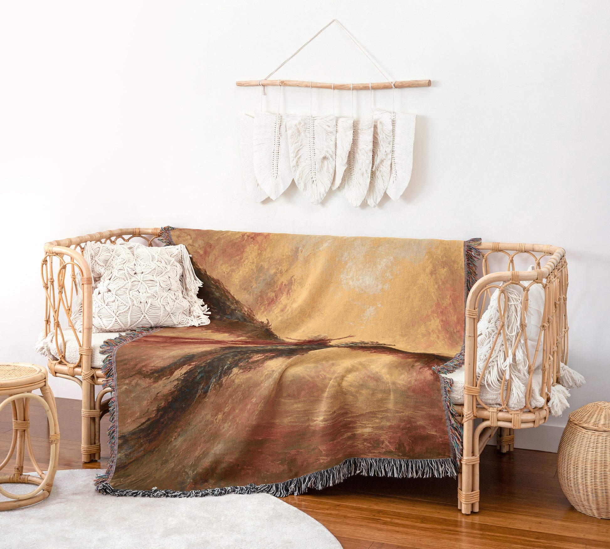 a cozy living room with a wicker sofa adorned with a colorful throw blanket and a wooden wall hanging with white feathers.