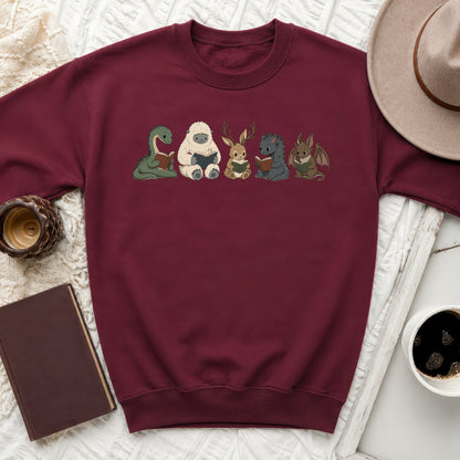 Maroon sweatshirt with a print of mythical creatures reading books.