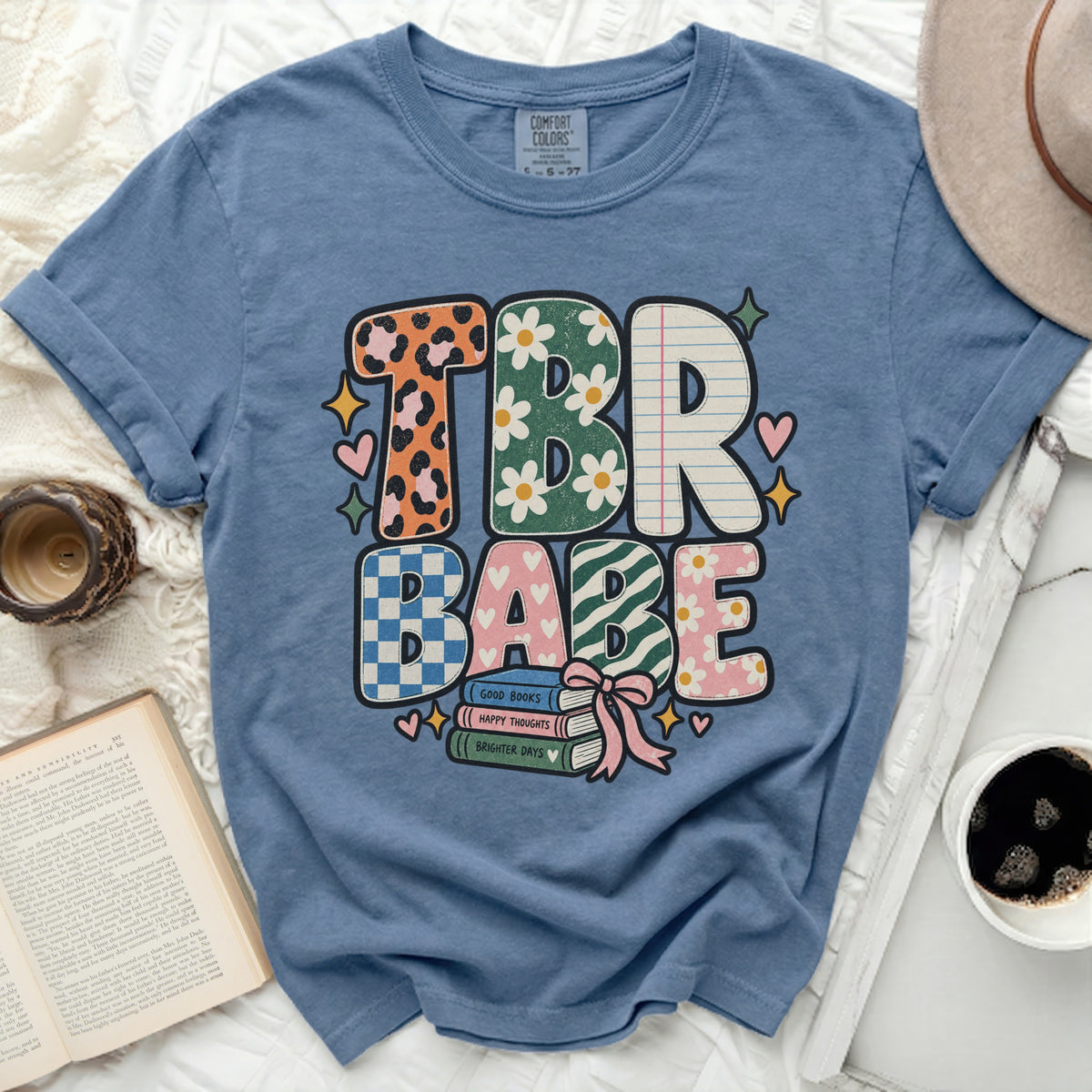 TBR BABE text graphic on a blue comfort colors t-shirt with stacked books.