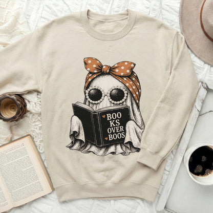 Ghost reading a book with text "Books Over Boos" on a cream sweatshirt.