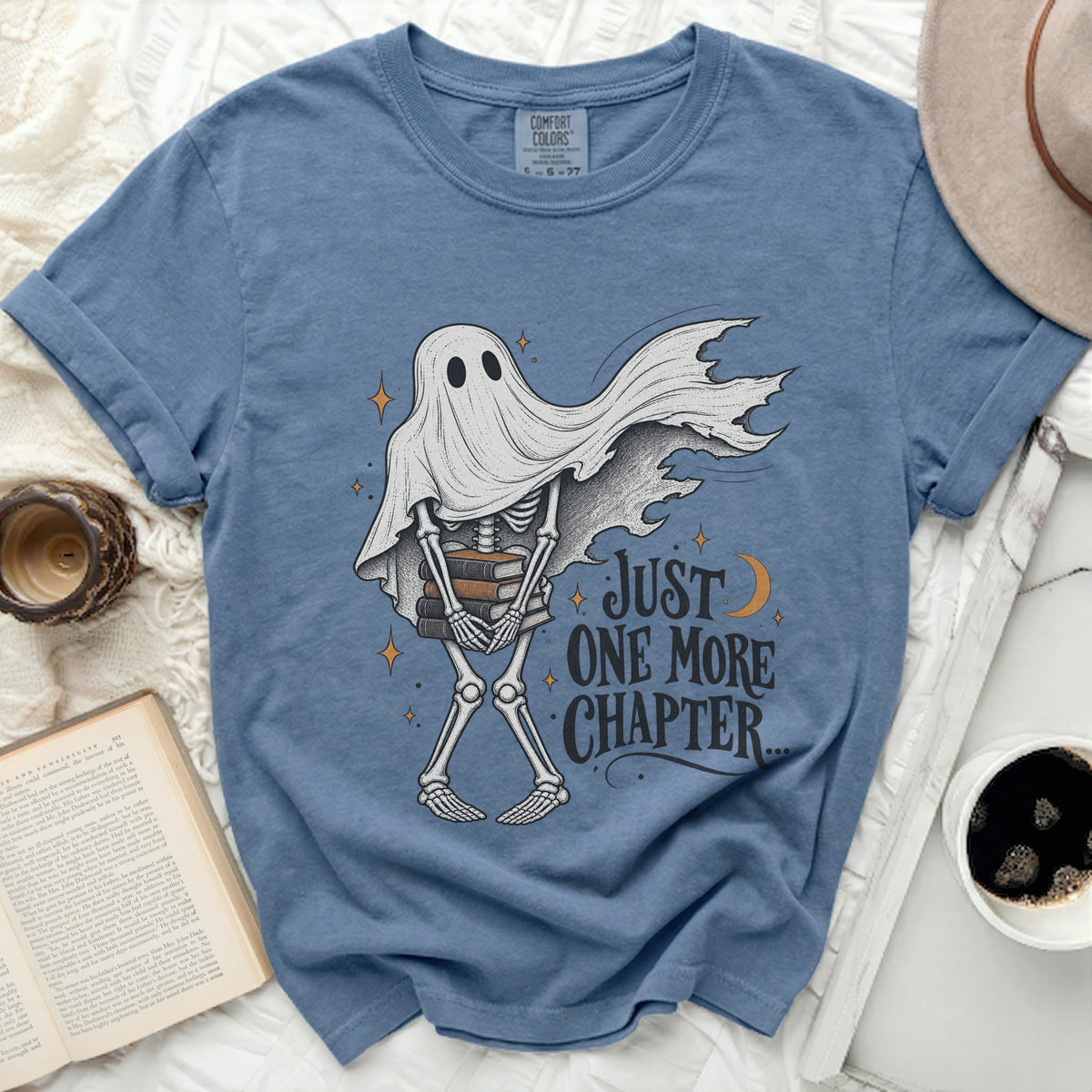 Skeleton ghost wearing a sheet holds books and says "Just One More Chapter".