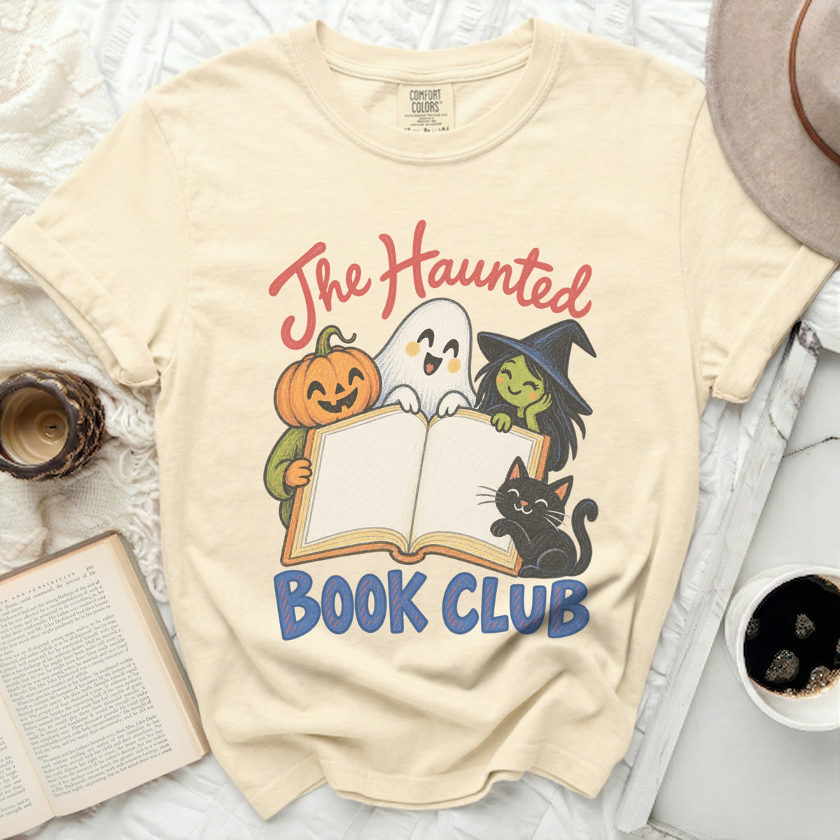 Light yellow t-shirt with "The Haunted Book Club" graphic featuring a pumpkin, ghost, witch, and cat.