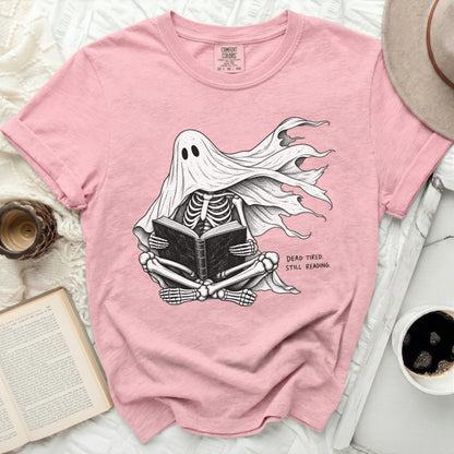 Pink t-shirt with skeleton ghost reading a book and text "DEAD TIRED. STILL READING."