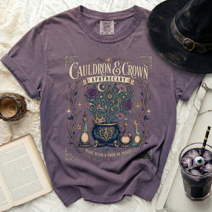 Purple t-shirt with "Cauldron & Crown Apothecary" graphic.