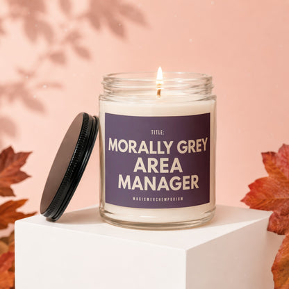 Candle with "Morally Grey Area Manager" text, burning flame, and autumnal leaves.