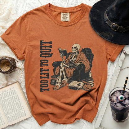 Skeleton wearing robe and slippers reads books with "Too Lit To Quit" text.