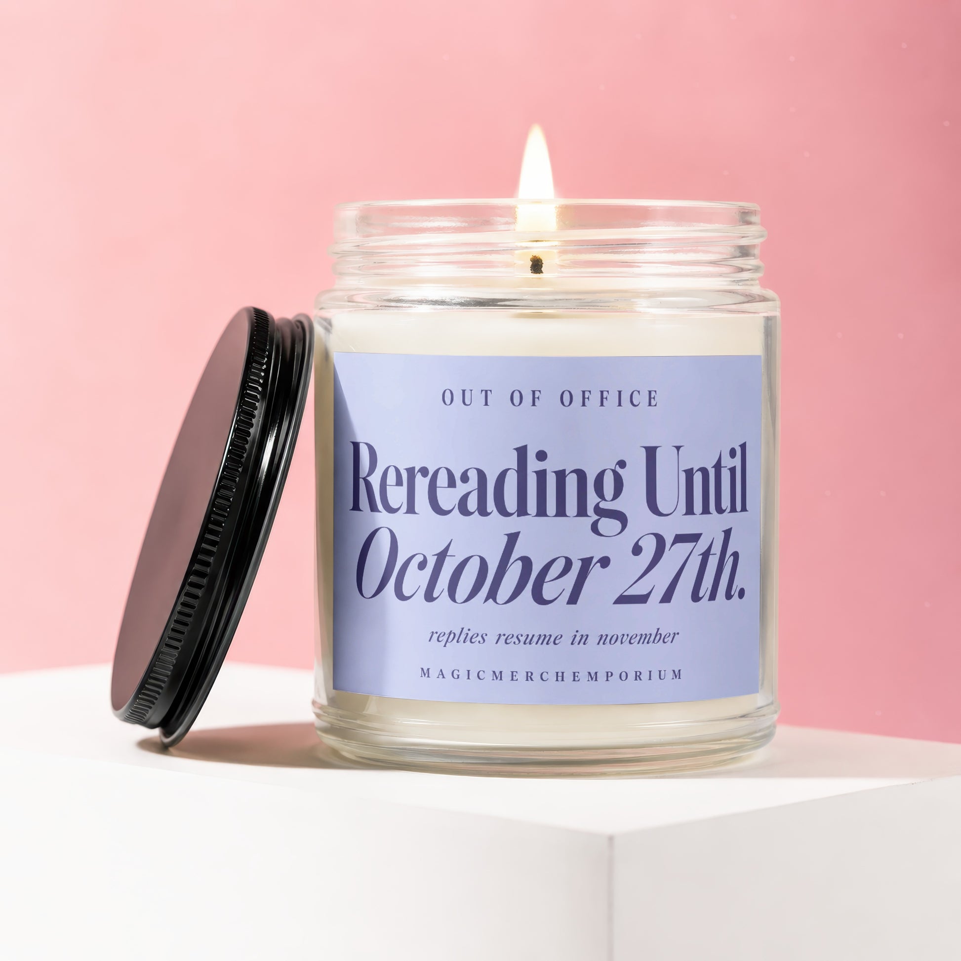Scented candle reading "Rereading Until October 27th." with lit wick.