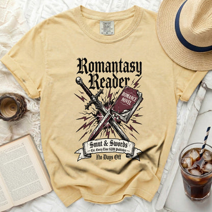 Yellow t-shirt with "Romantasy Reader Smut & Swords No Days Off" graphic.