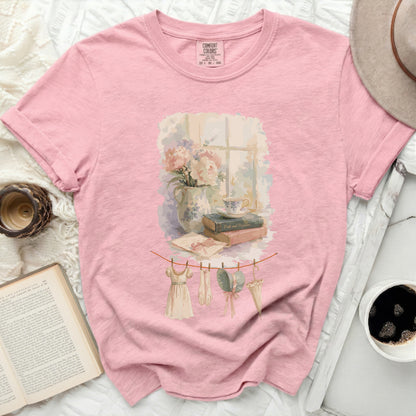 Pink t-shirt with a watercolor print of a window scene and clothesline.