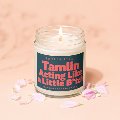 Glass jar candle with lit wick, reads "Smells Like Tamlin Acting Like a Little B*tch"