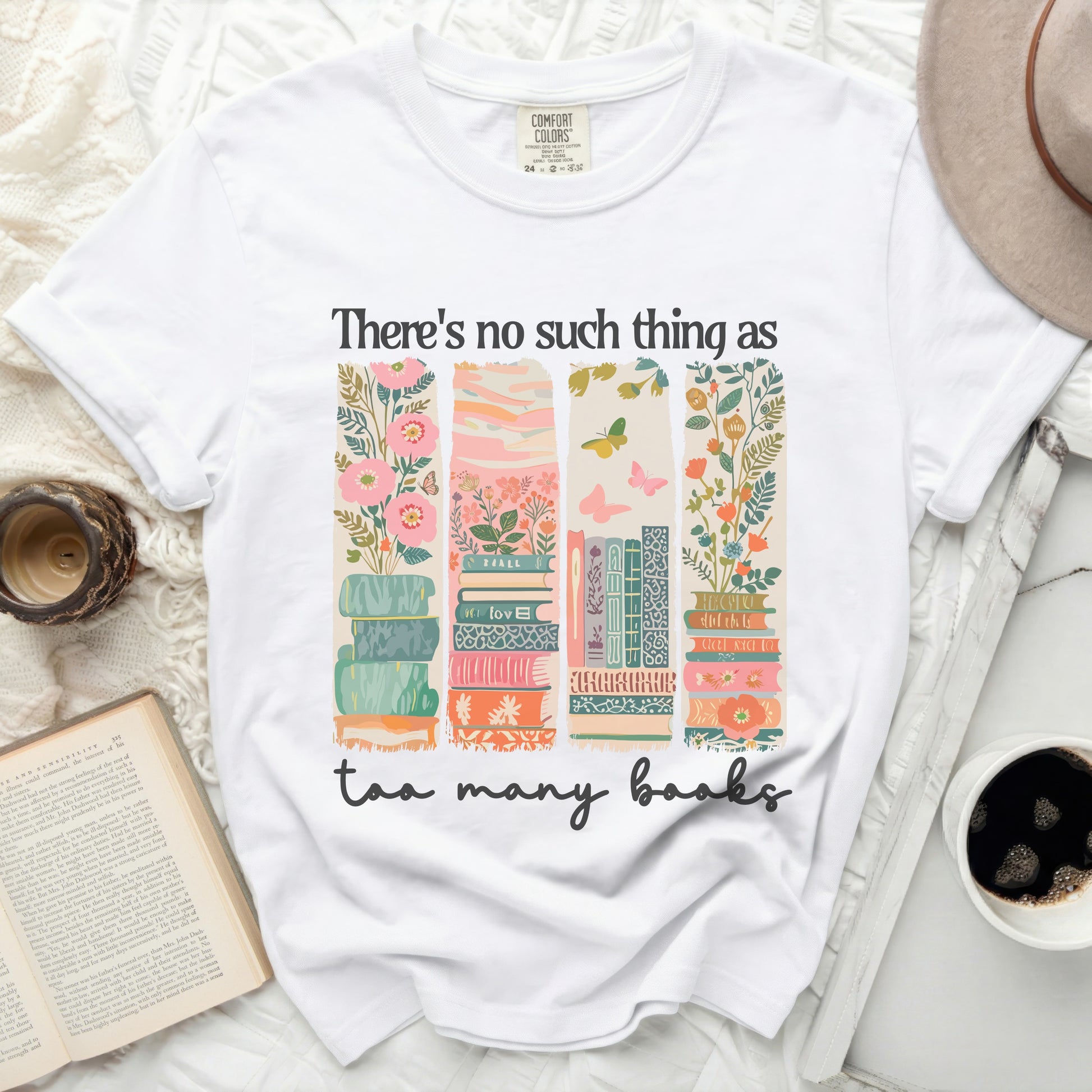 White t-shirt with stacked books and floral illustration, "There's no such thing as too many books" text.