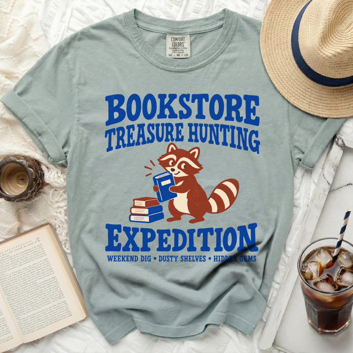T-shirt with raccoon, books, and text: "BOOKSTORE TREASURE HUNTING EXPEDITION"