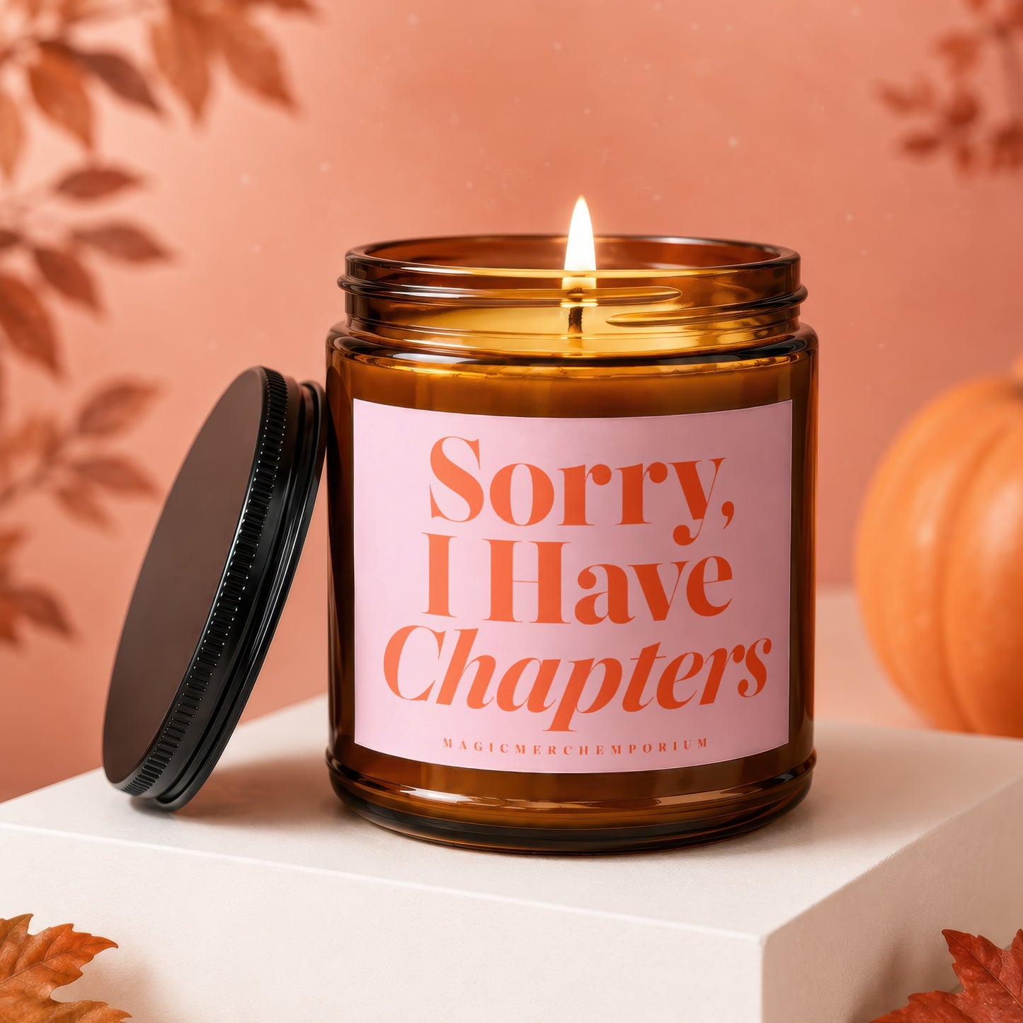 Amber candle with lit wick, pink label saying "Sorry, I Have Chapters".