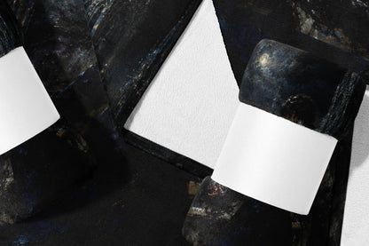 Dark textured blanket with celestial print and white bands on a white background.
