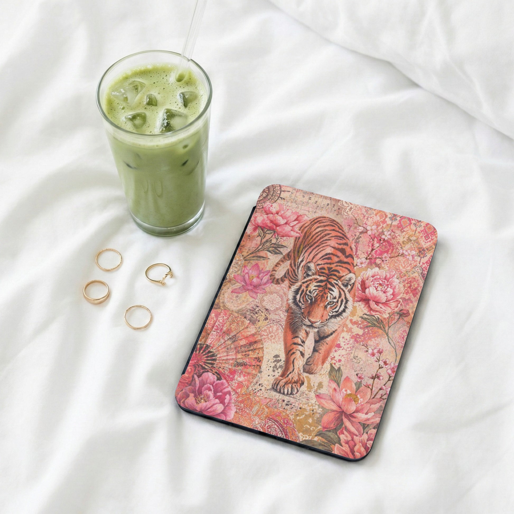 Tiger with floral pattern mousepad on white fabric, next to iced drink and rings.