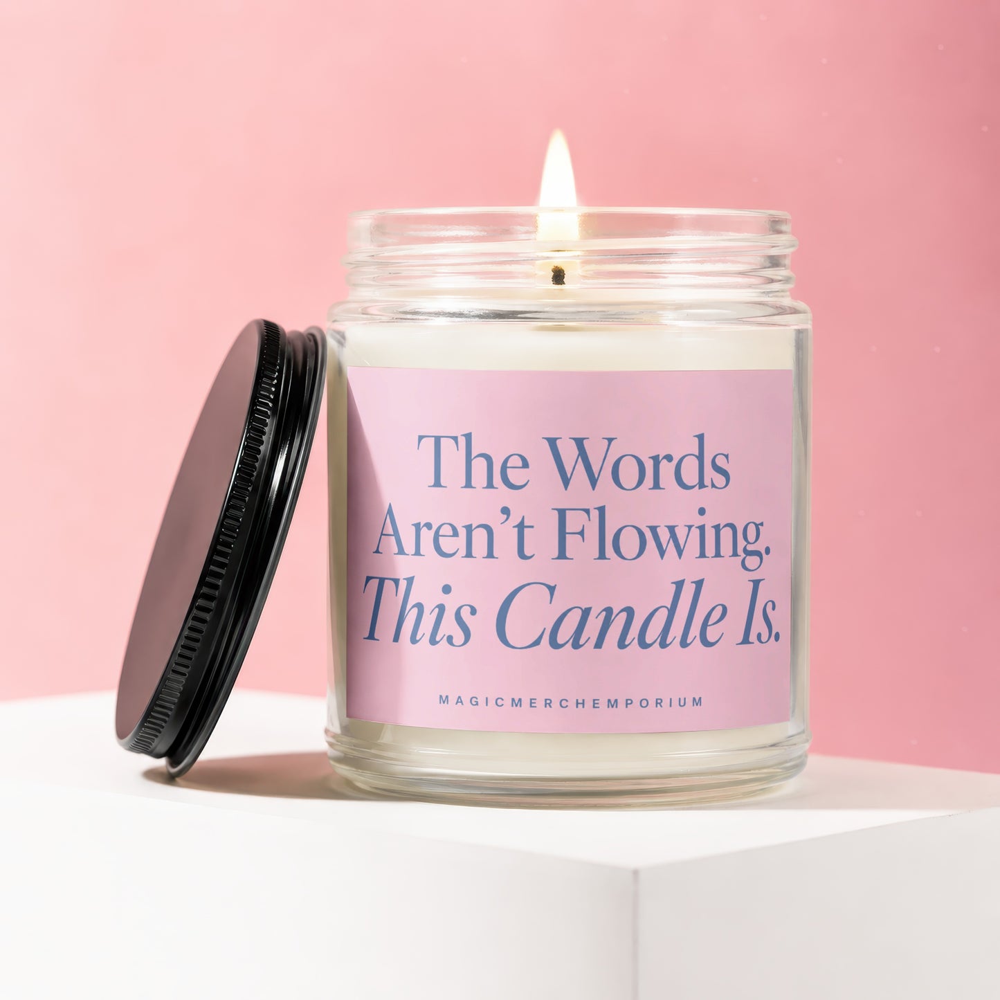 Jar candle with pink label that reads: The Words Aren't Flowing. This Candle Is.