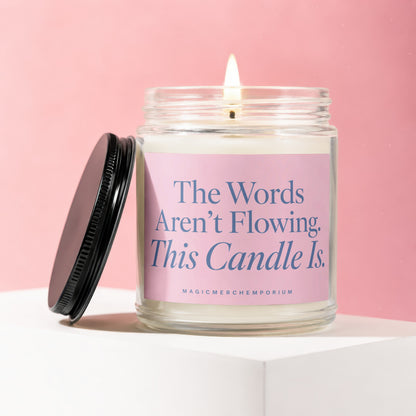 Jar candle with pink label that reads: The Words Aren't Flowing. This Candle Is.