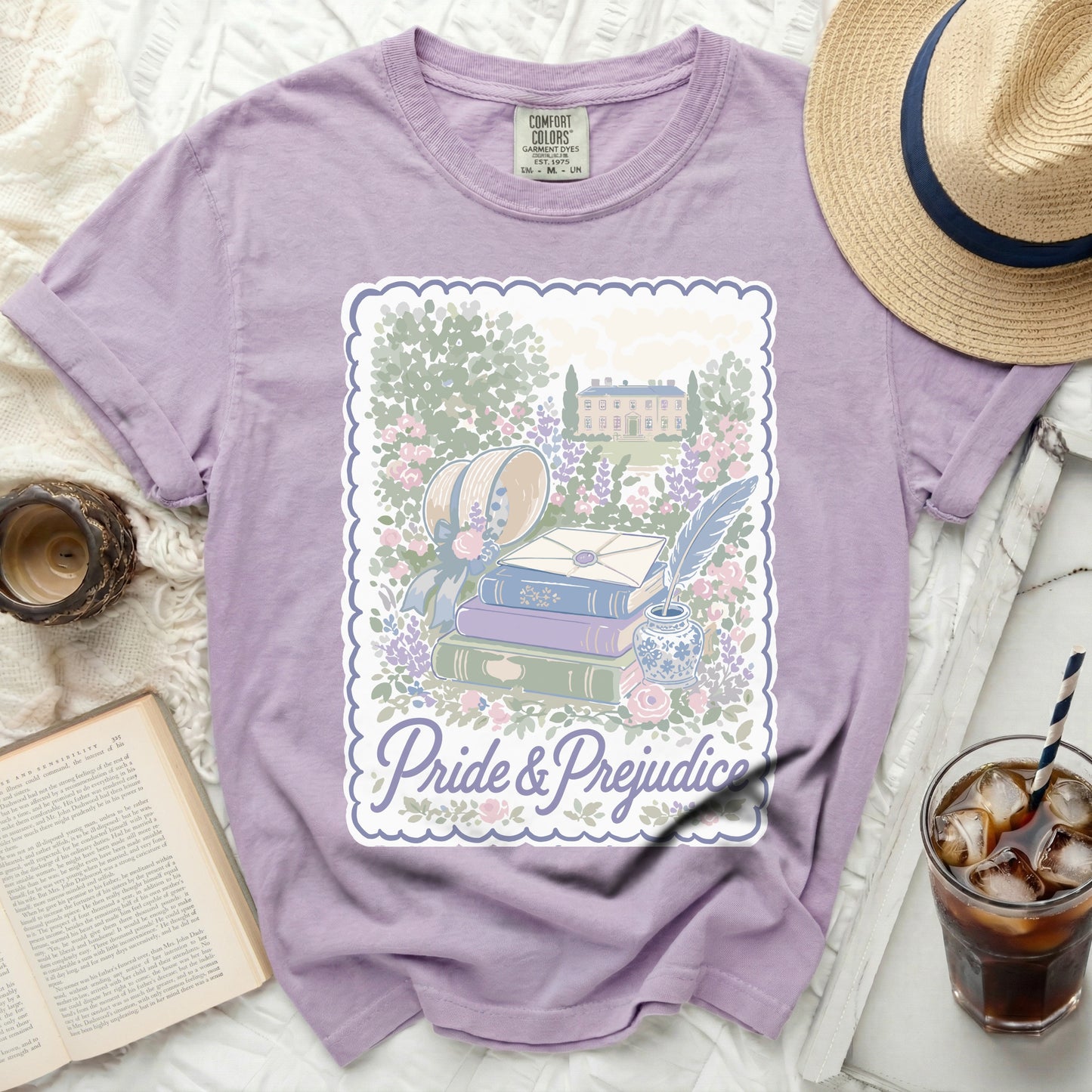 Purple t-shirt with "Pride & Prejudice" design of books and manor.