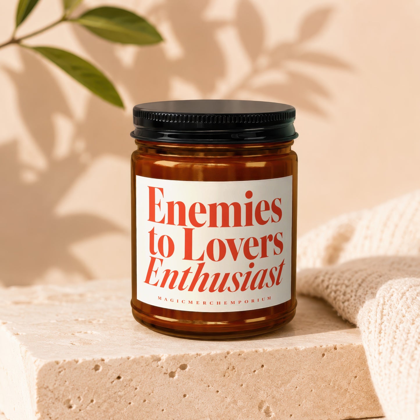 Candle with red text "Enemies to Lovers Enthusiast" on a white label.