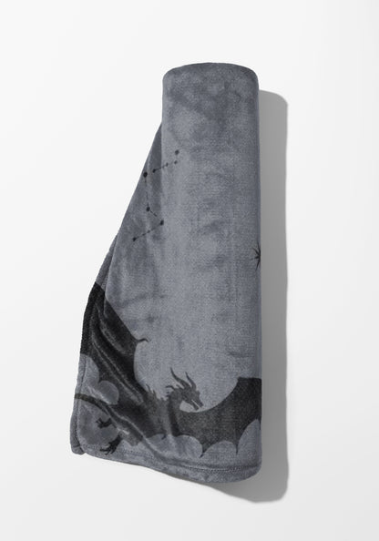 Rolled gray blanket with a black dragon and constellation pattern.