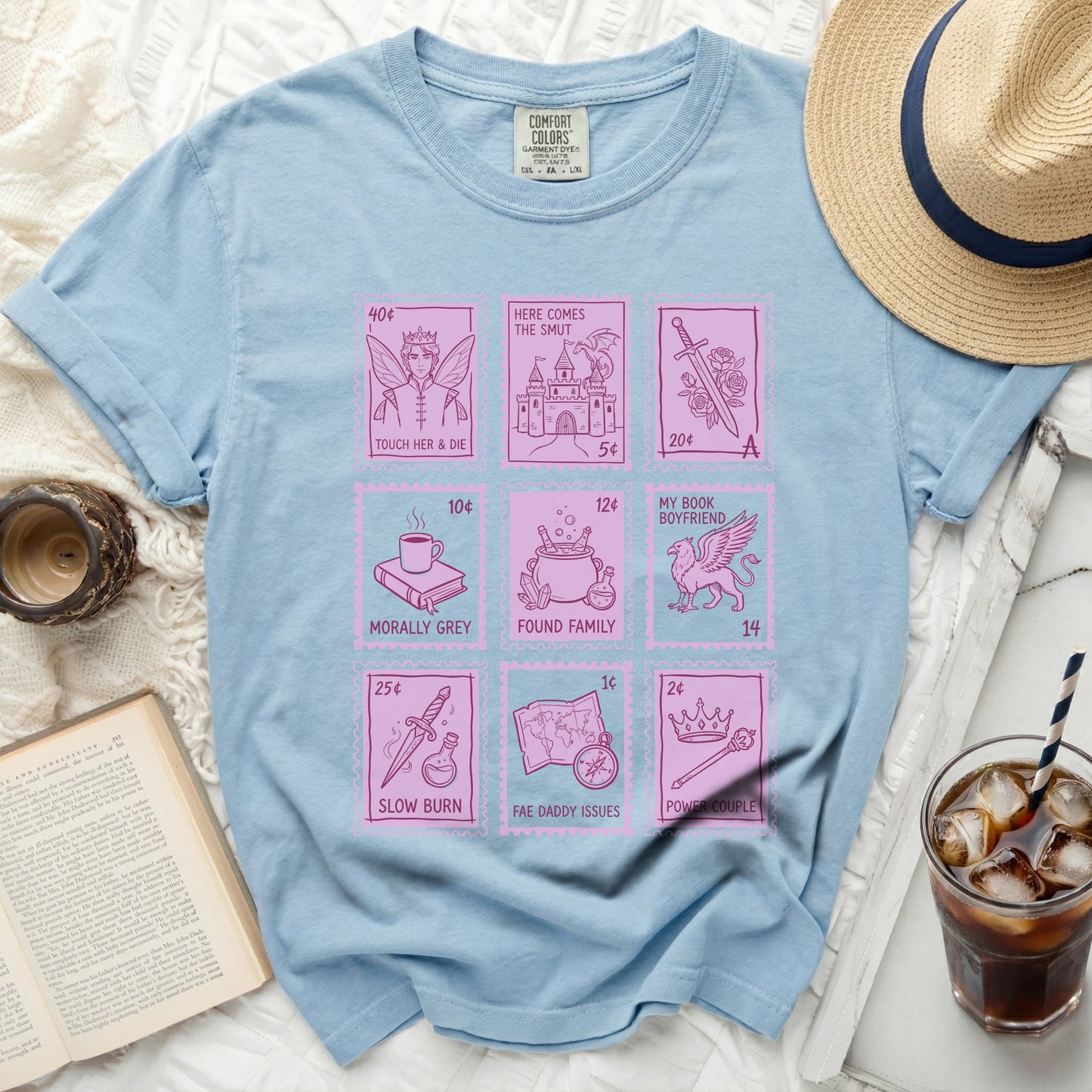 Light blue t-shirt with pink fairy tale and romance book stamp graphics.