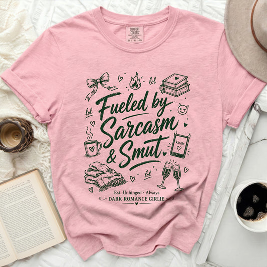 Pink t-shirt with "Fueled by Sarcasm & Smut" text and graphic illustrations.