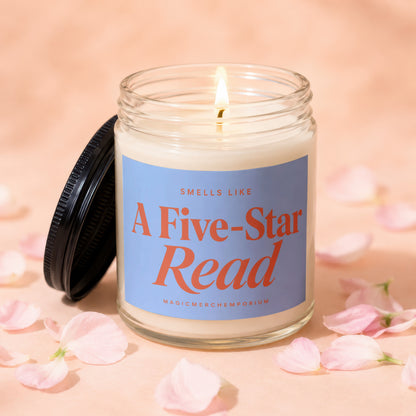 Lit candle in glass jar with a blue label reading "Smells Like A Five-Star Read."
