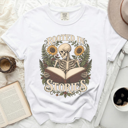 Skeleton reading a book with "Rooted in Stories" text and sunflowers.