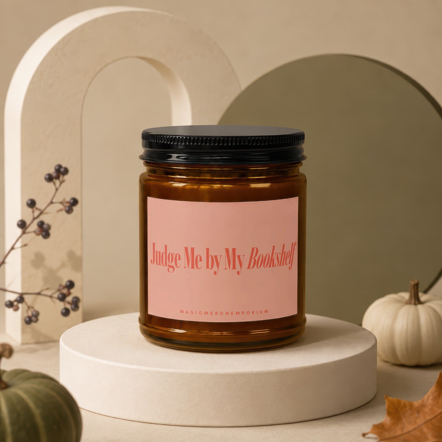 Amber candle with pink label reading "Judge Me by My Bookshelf" and "MAGICMERCHÉMPORIUM".
