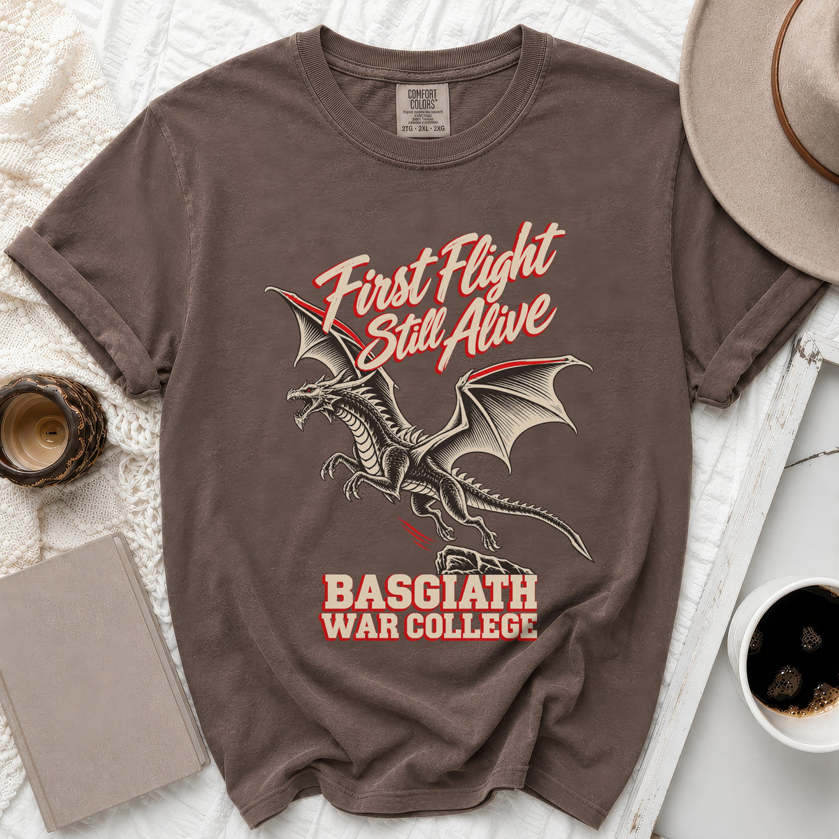 Brown t-shirt with dragon graphic and text "First Flight Still Alive Basgiath War College".