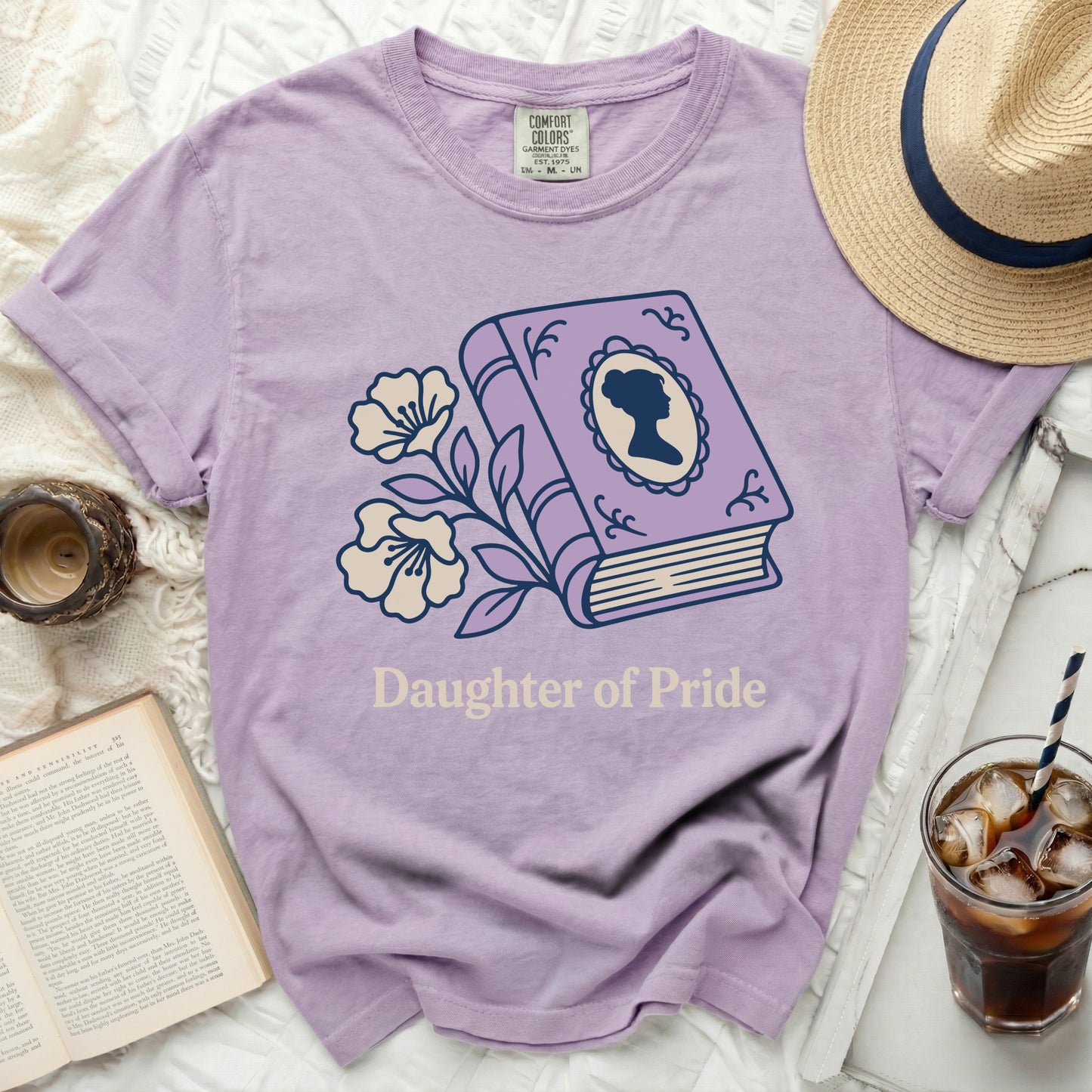 Lavender shirt with "Daughter of Pride" and book graphic.