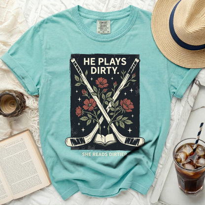 "He Plays Dirty. She Reads Dirtier." text on teal t-shirt with crossed hockey sticks and flowers.