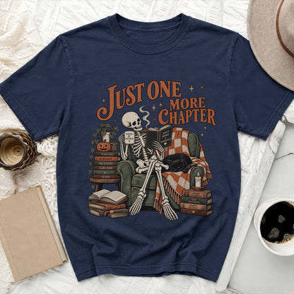 Skeleton reading a book with "Just One More Chapter" text, "Fueled by Fiction" mug, and books.