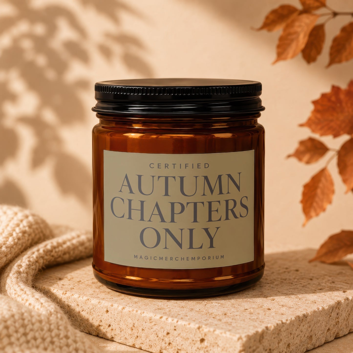 Amber candle with "Autumn Chapters Only" label, featuring autumn leaves and knit fabric.