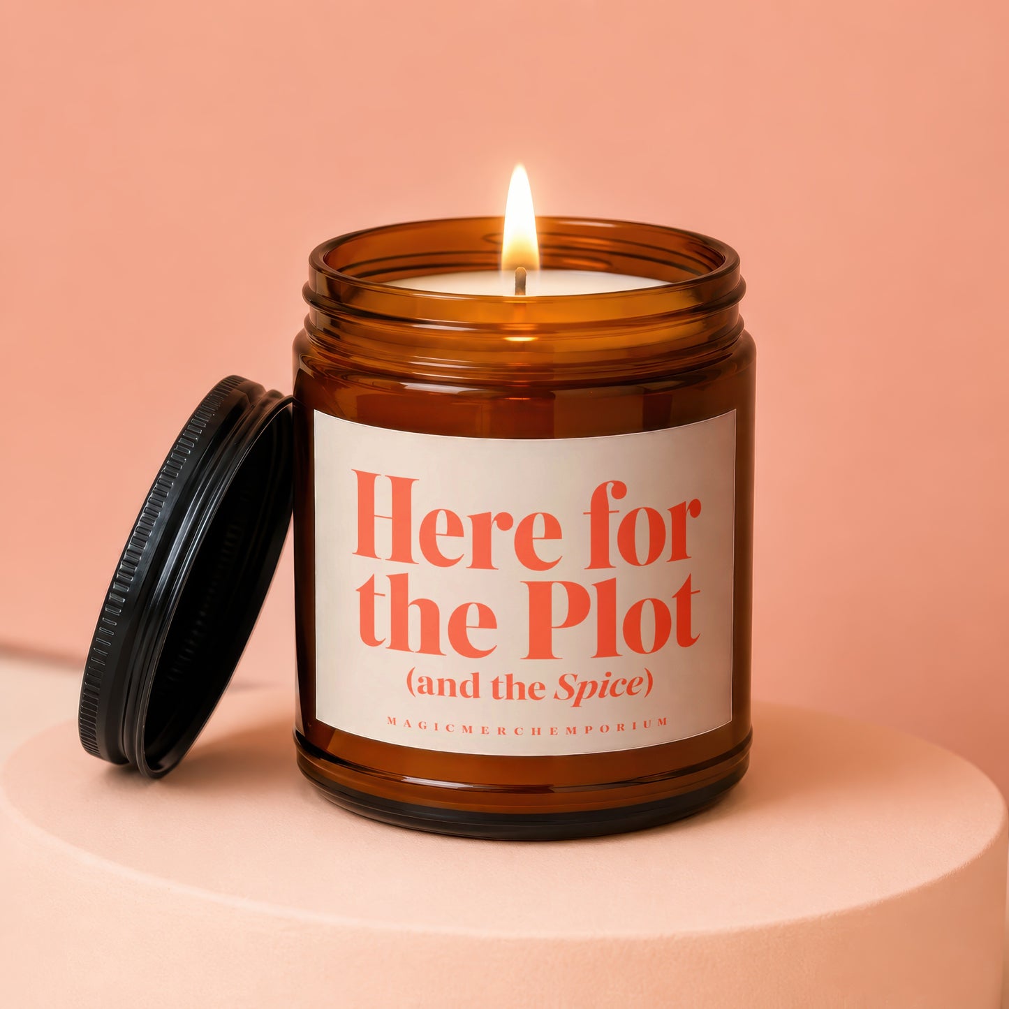 Amber jar candle with lit flame and lid, reads "Here for the Plot (and the Spice)".