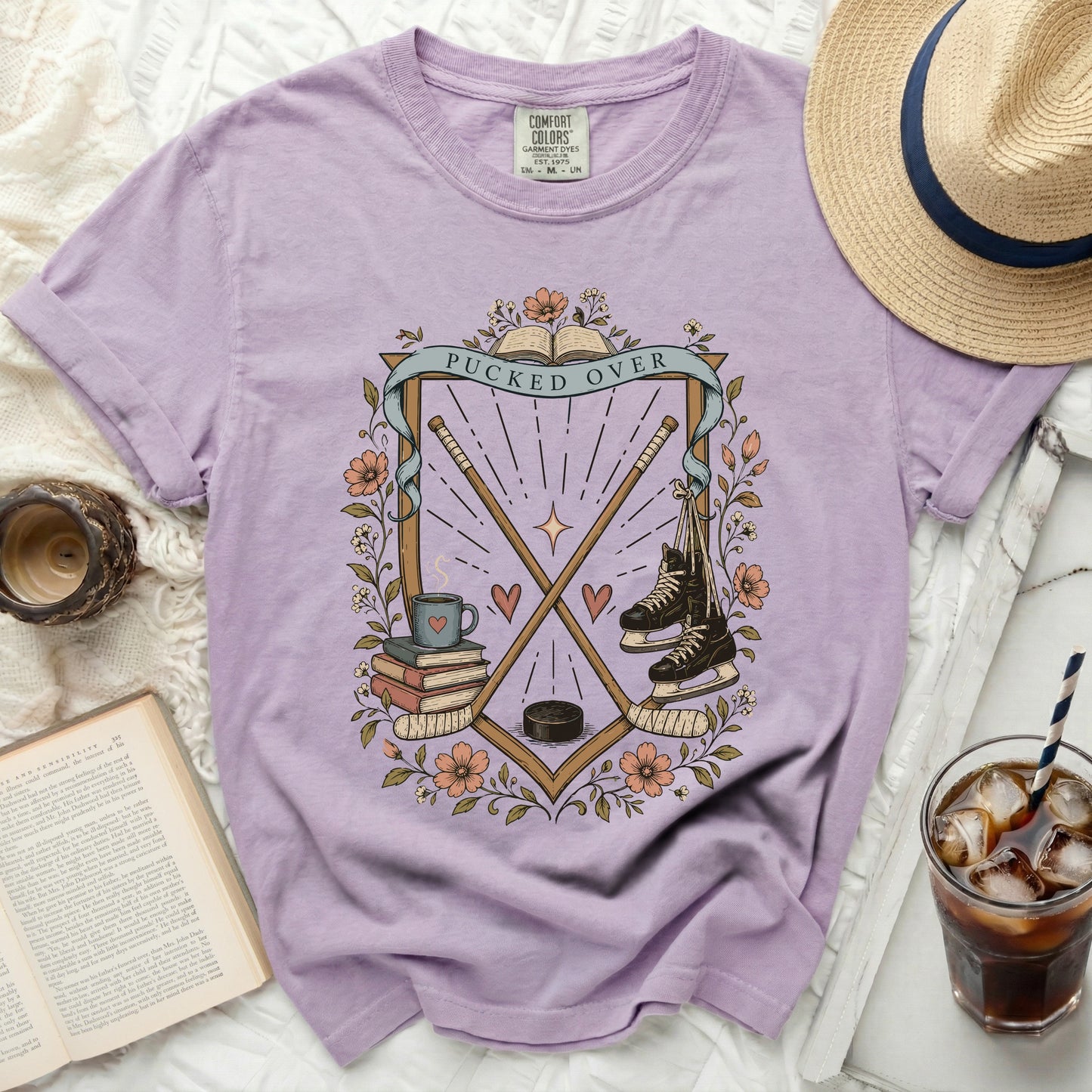 Lavender t-shirt with hockey sticks, skates, and books design.