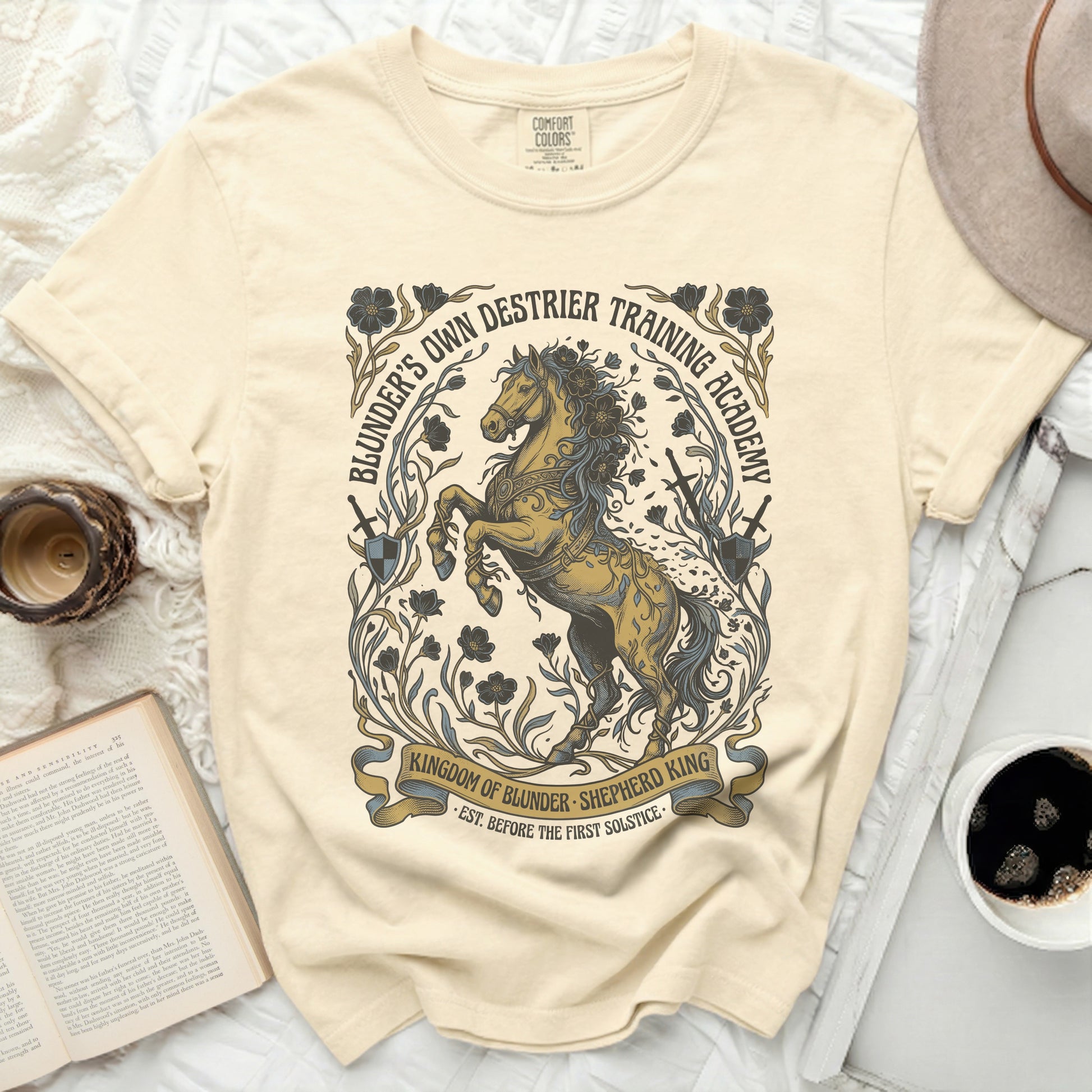 Cream t-shirt with a golden horse and academy text graphic.