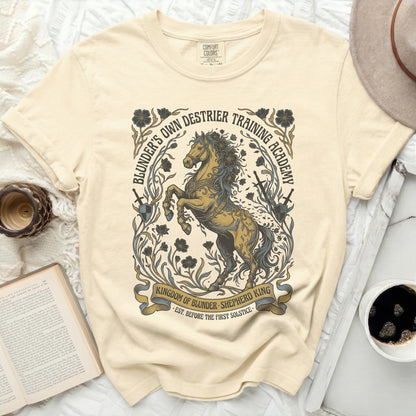 Cream t-shirt with a golden horse and academy text graphic.