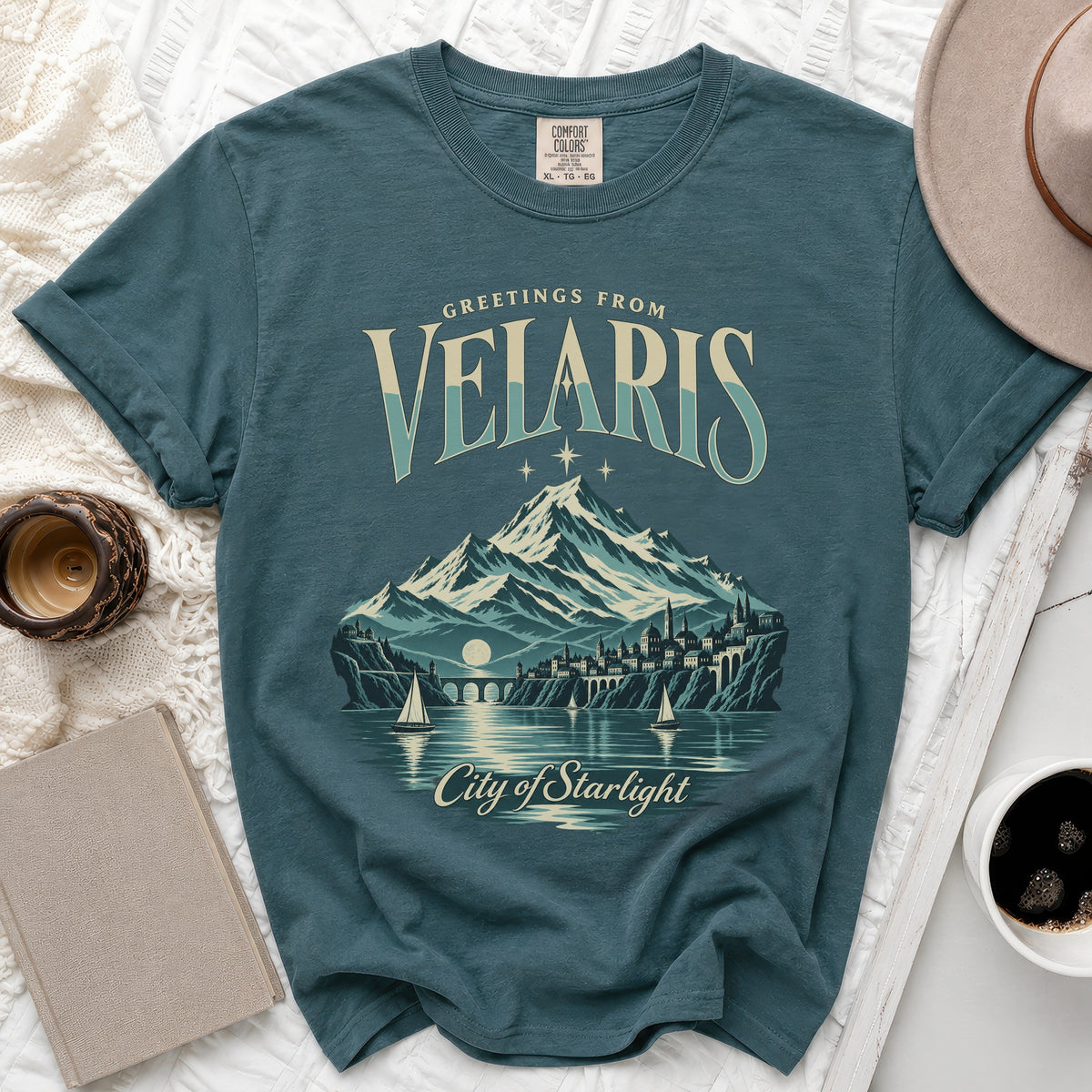 Teal t-shirt with "Greetings from Velaris, City of Starlight" graphic.