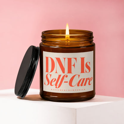 Amber candle with lit wick and black lid, reads "DNF Is Self-Care"